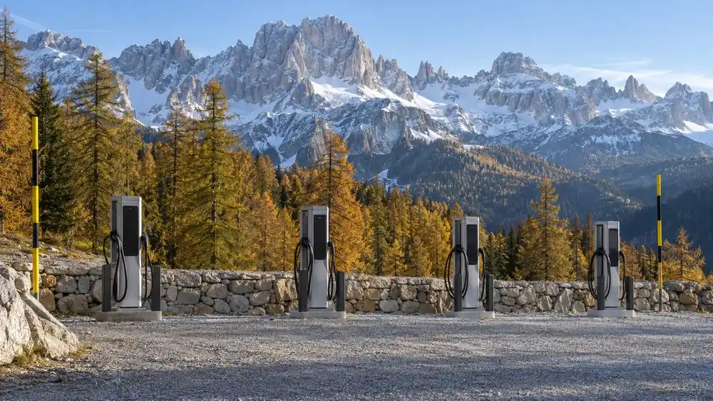 Řada prázdných nabíjecích stojanů pro elektromobily u jihotyrolské horské silnice pod dolomitskými vrcholy